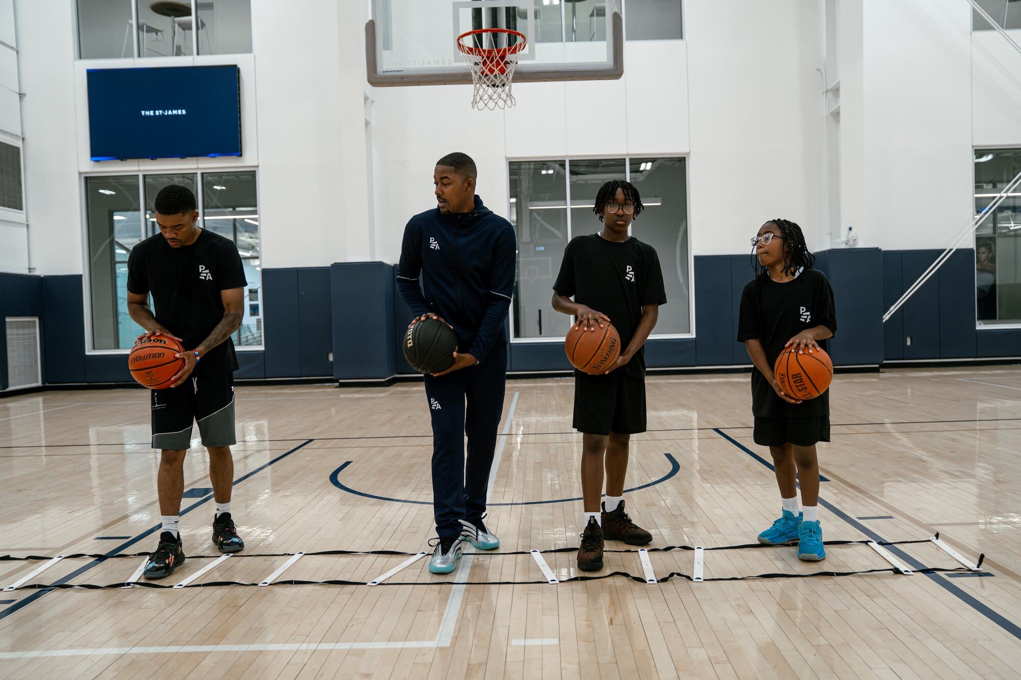 Rashad Petty coaching three athletes through a basketball drill