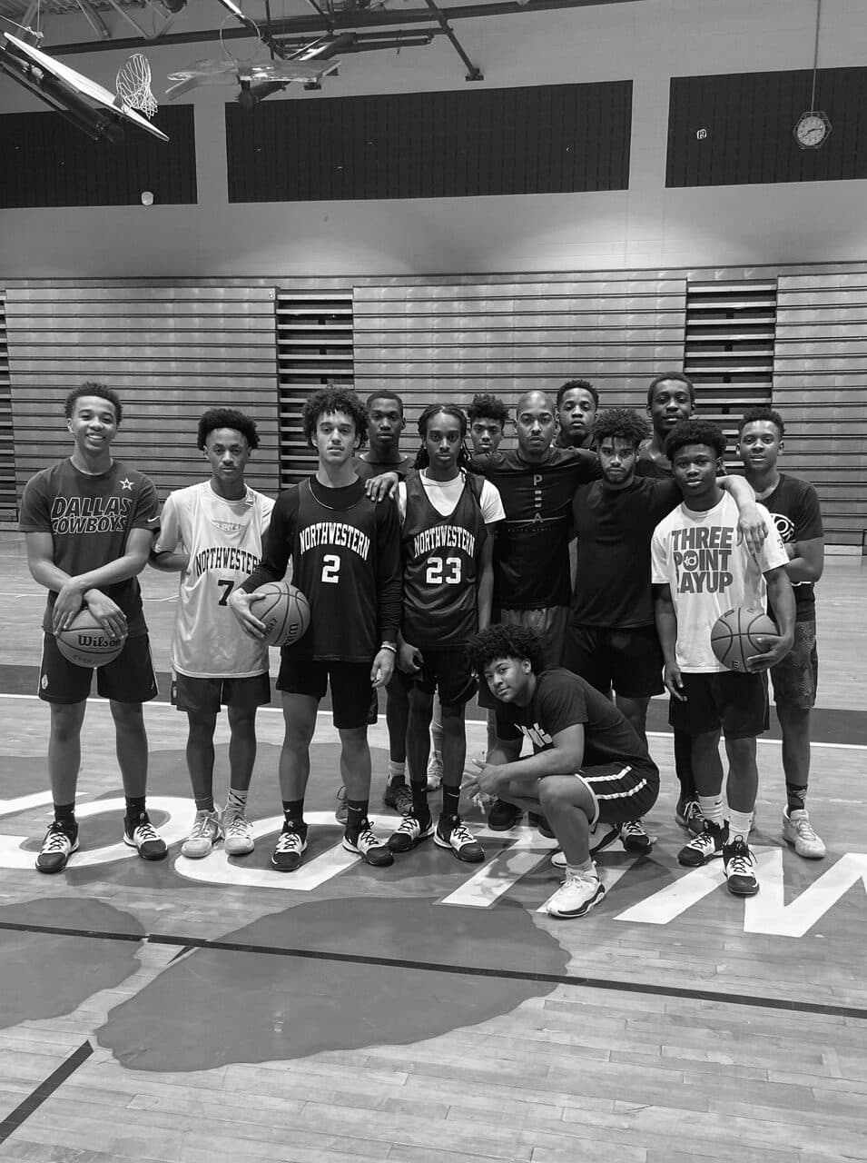 A youth basketball team posed on a court with basketballs