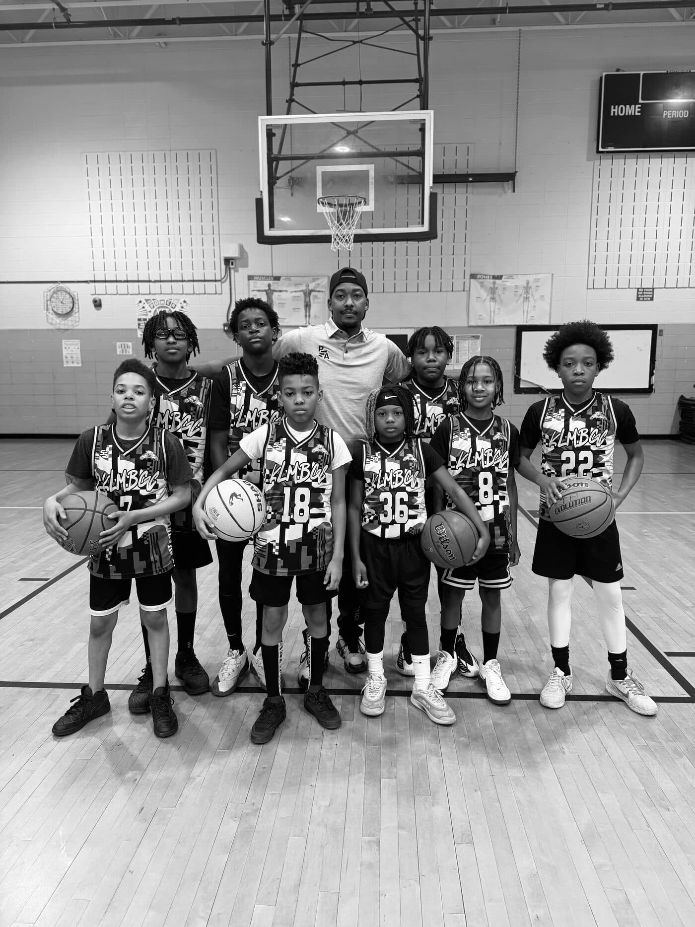 A youth team in Petty Athletics jerseys posed in front of a basketball hoop