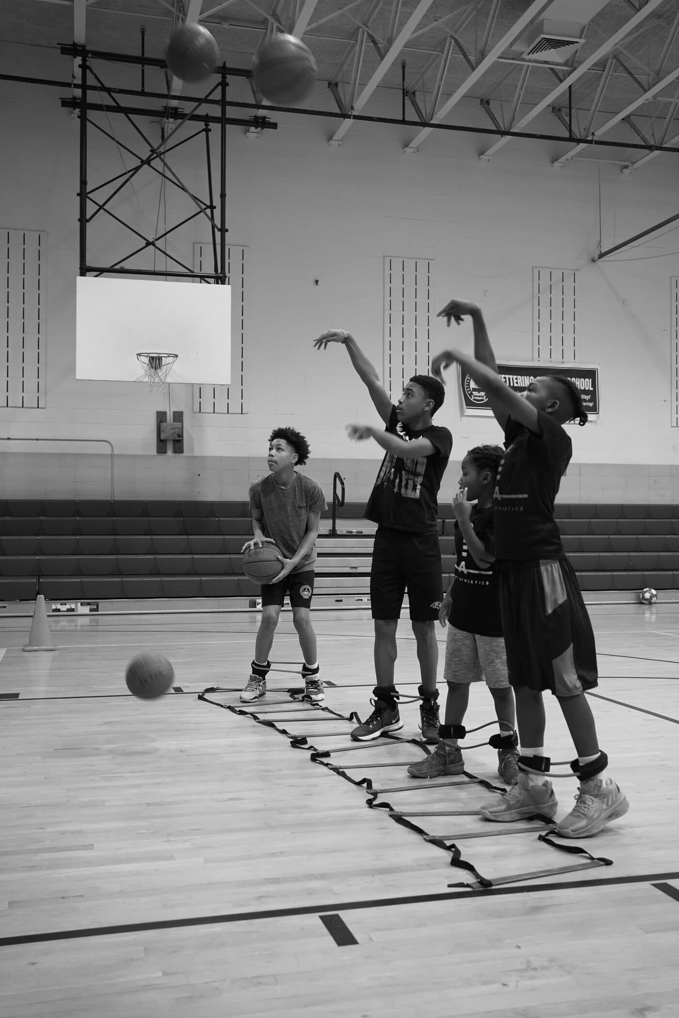 Young Petty Athletics players holding their shooting follow-through during a form drill over an agility ladder