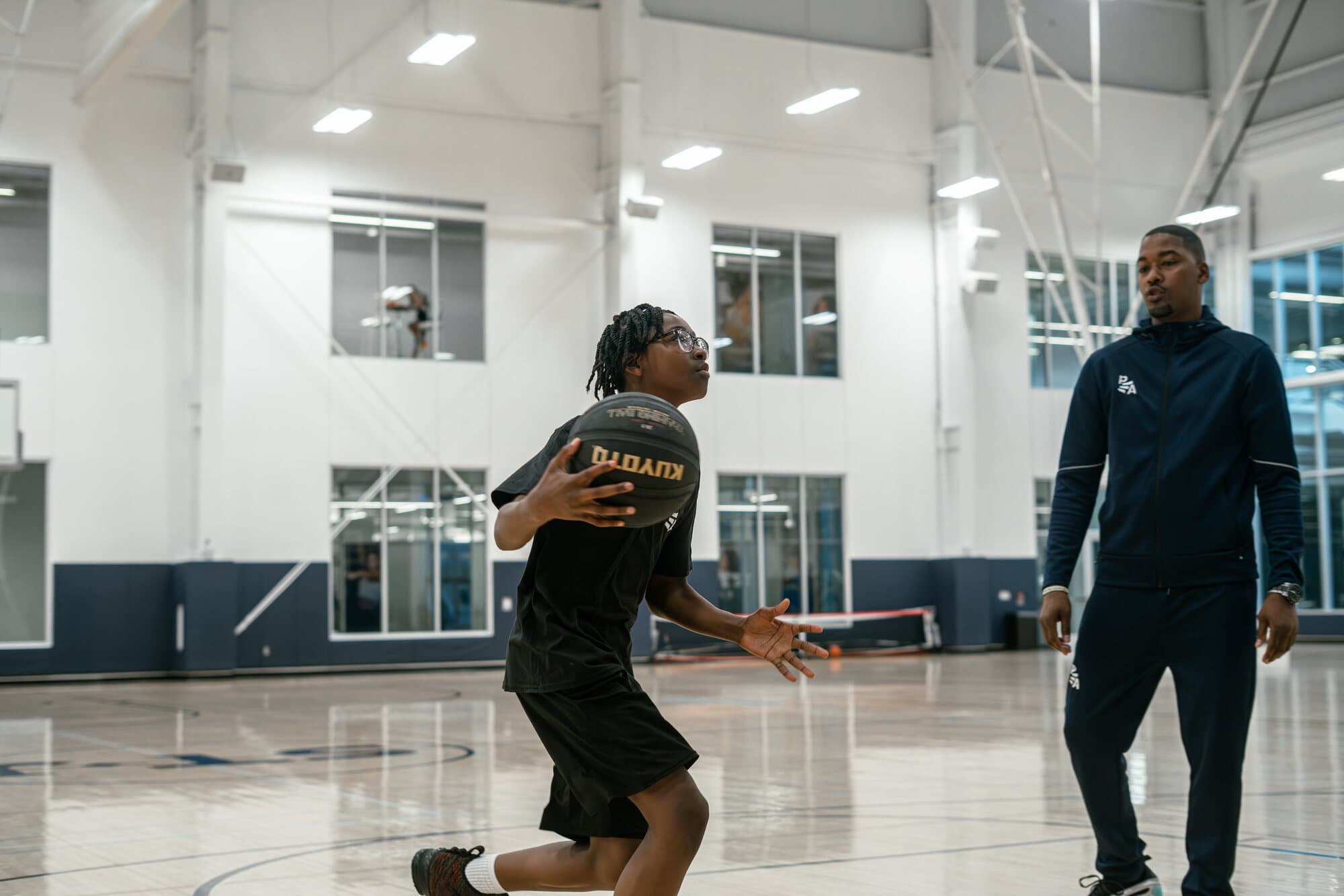 Rashad Petty observing a youth athlete during a basketball drill
